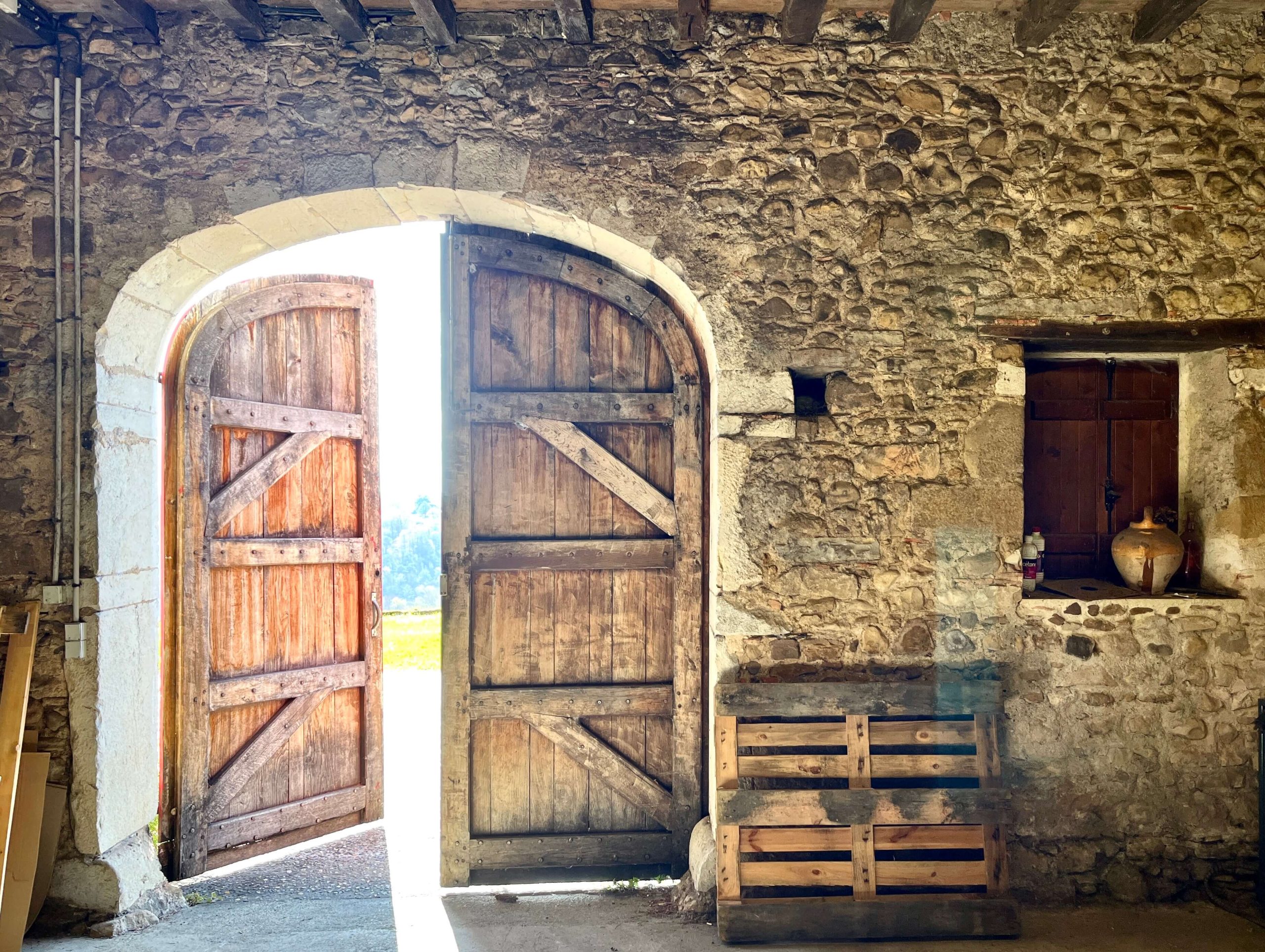 Stone building with wooden door open at Camin Larredya